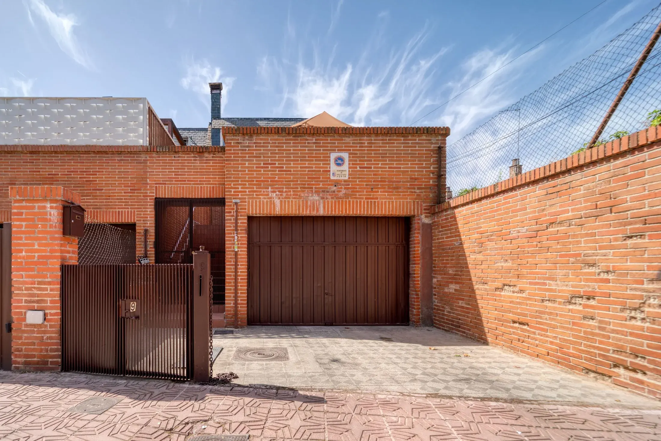 Concrete courtyard and paved approach outside a brick residence